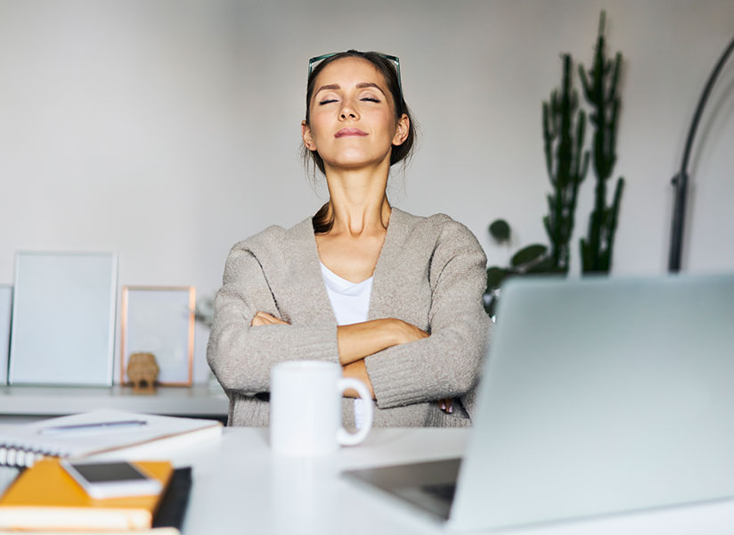 Relaxed woman sitting back with her arms crossed in front of her desk in her office