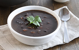 a bowl of black bean soup garnished with cilantro