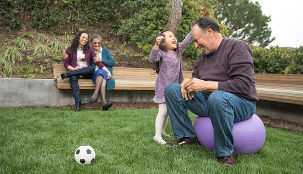 extended family playing soccer in a park