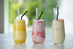 three varieties of smoothies in glasses with straws