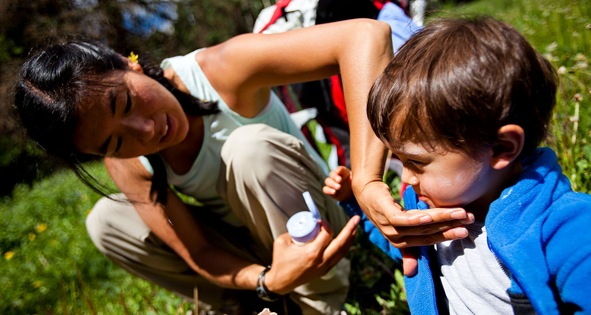 mother applying sunscreen to son before going on a hike
