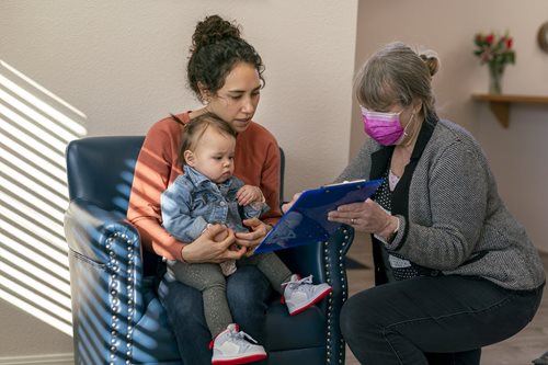 Social worker helping mother holding child with paperwork