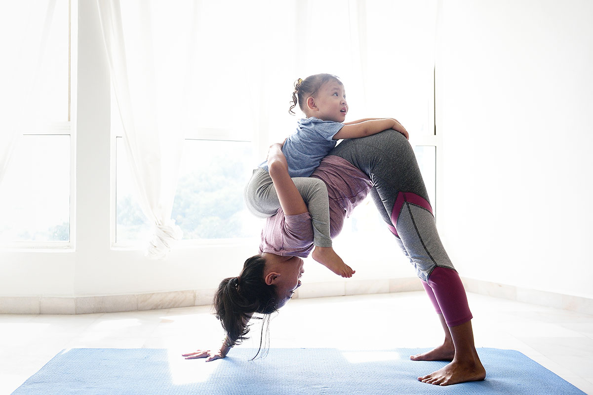 woman in downward dog pose with young daughter