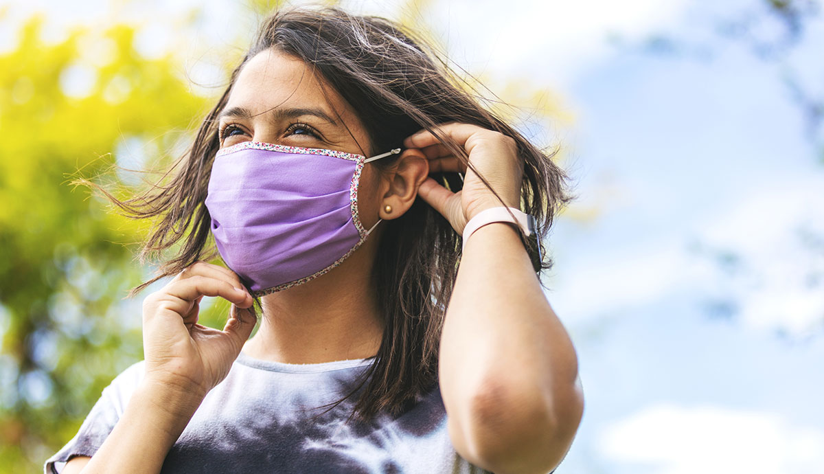 young woman wearing a purple mask outside