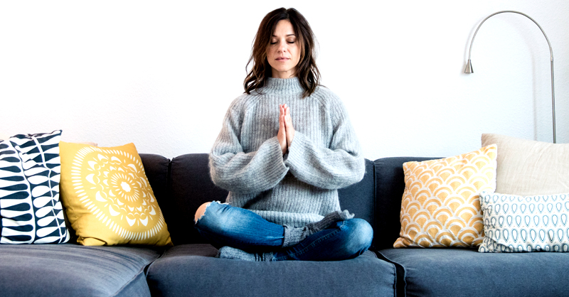 woman meditating at home on her couch