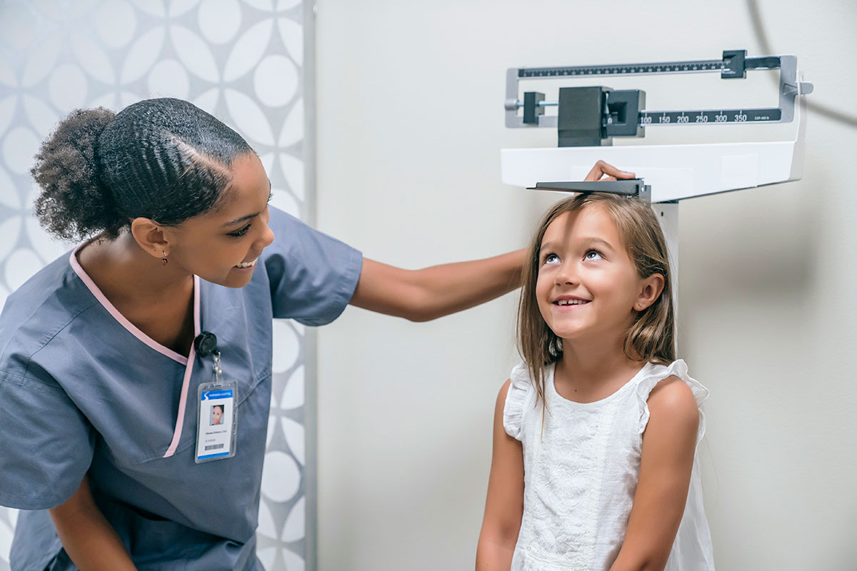 a nurse measuring the height and weight of young girl patient