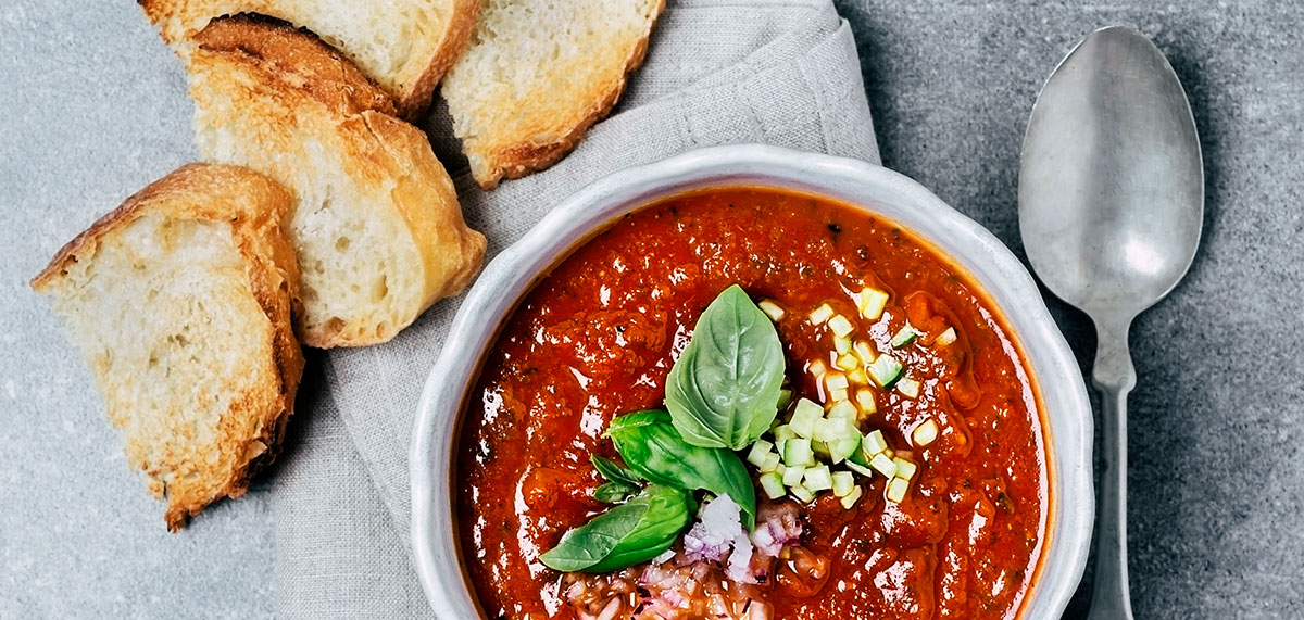 a bowl of tomato soup with garnishes and toasted bread