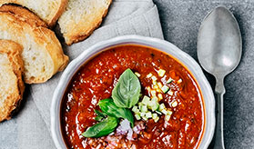 a bowl of tomato soup with garnishes and toasted bread