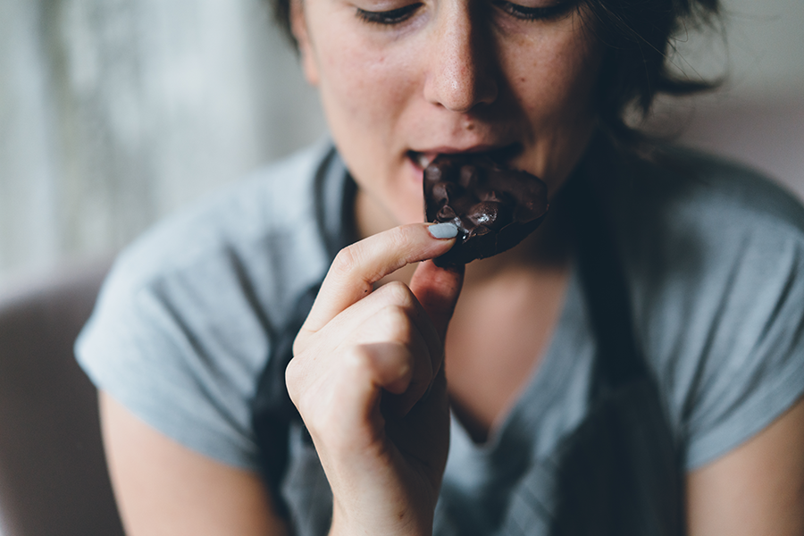 woman eating a piece of dark chocolate