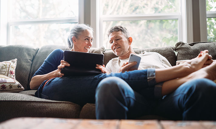 Couple at home looking at digital tools on a tablet and a phone