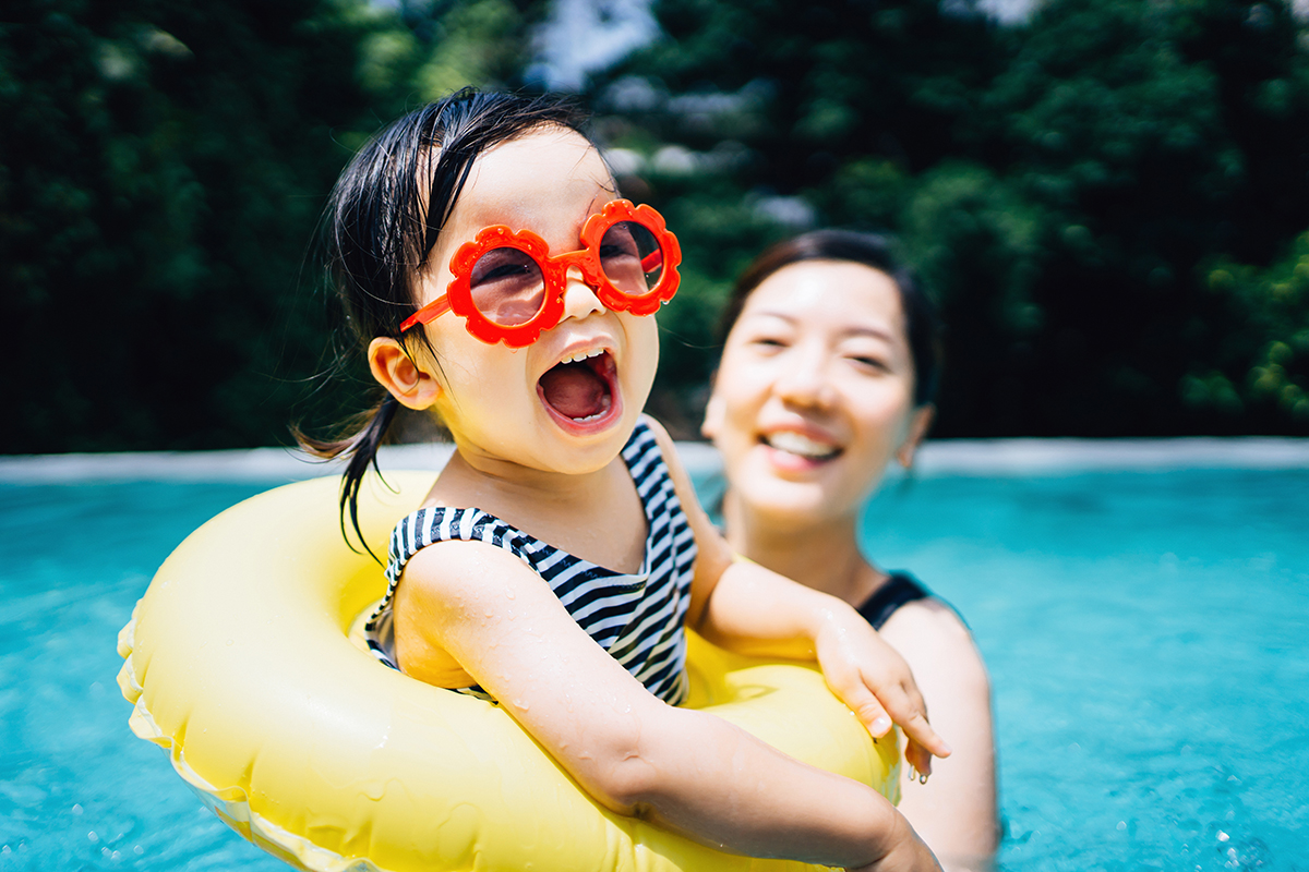 mom swimming in a pool with young daughter 